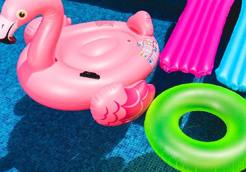 A pink flamingo float and some green, blue and yellow floats.